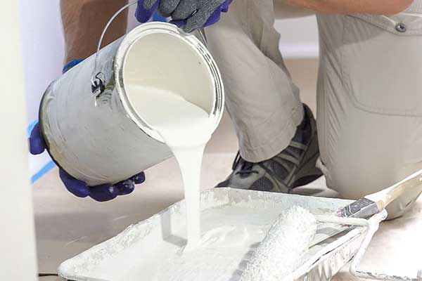 Worker pouring white paint into a tray